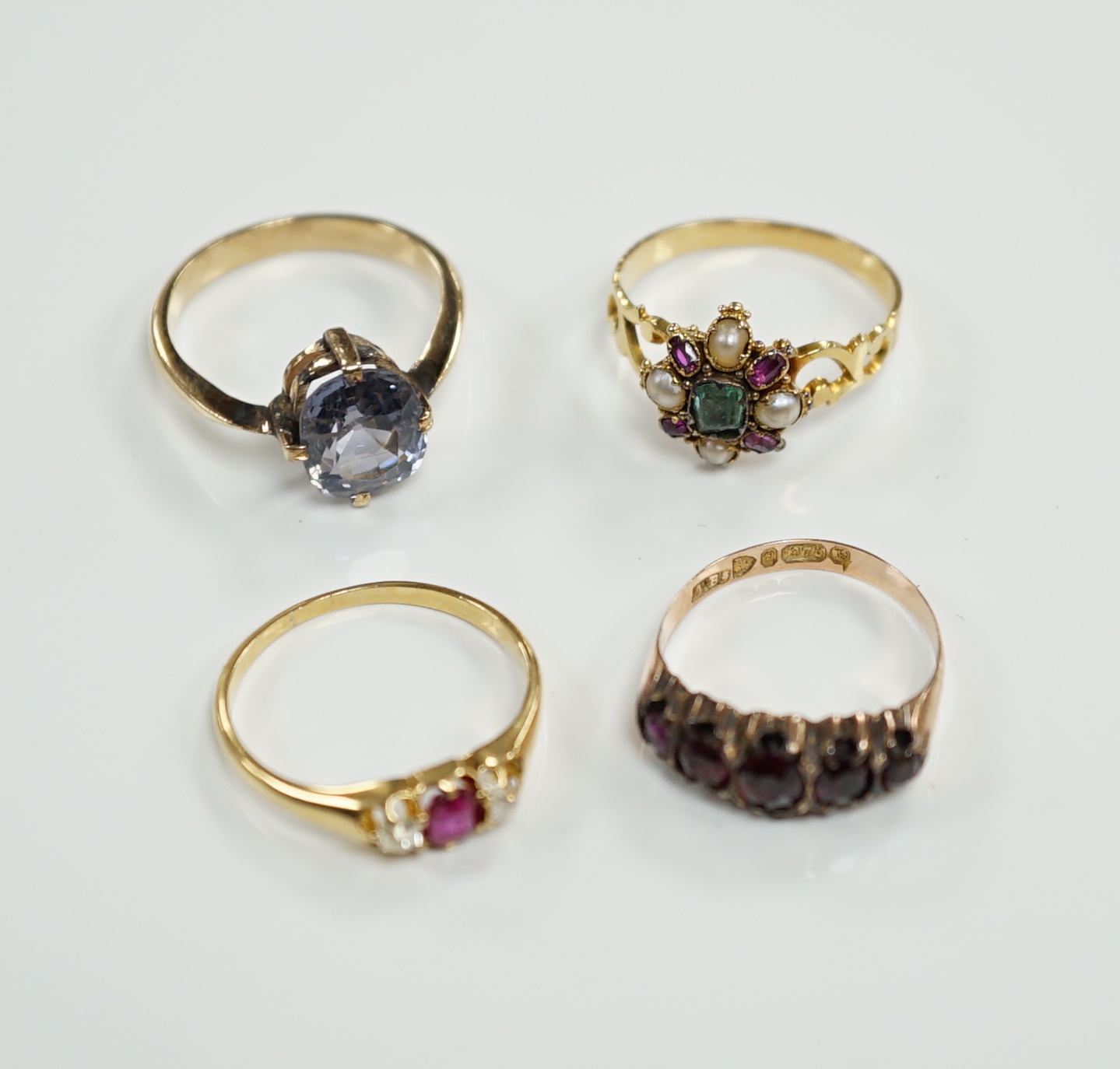 A late Victorian yellow metal, emerald, garnet and split pearl cluster set ring, in the Suffragette colours, size M/N and three other rings including Victorian 9ct gold and garnet set half hoop and 18ct, ruby and diamond